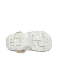 Semelle en caoutchouc blanc avec un motif de grip texturé, présentant des empreintes rondes et une finition lisse. Matériau semblable à de la fourrure attaché autour des bords.
