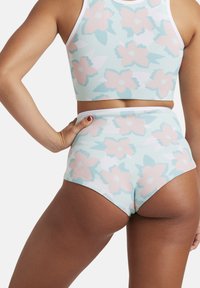 Květinový crop top a kalhoty s vysokým pasem v světle modré barvě, zdobené růžovými a zelenými květinovými vzory. Hladká, elastická textura látky.