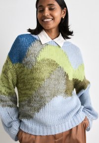 Pull en tricot avec un motif en vagues multicolores bleu, vert et beige. Coupe ample, poignets et ourlet côtelés avec une finition texturée.
