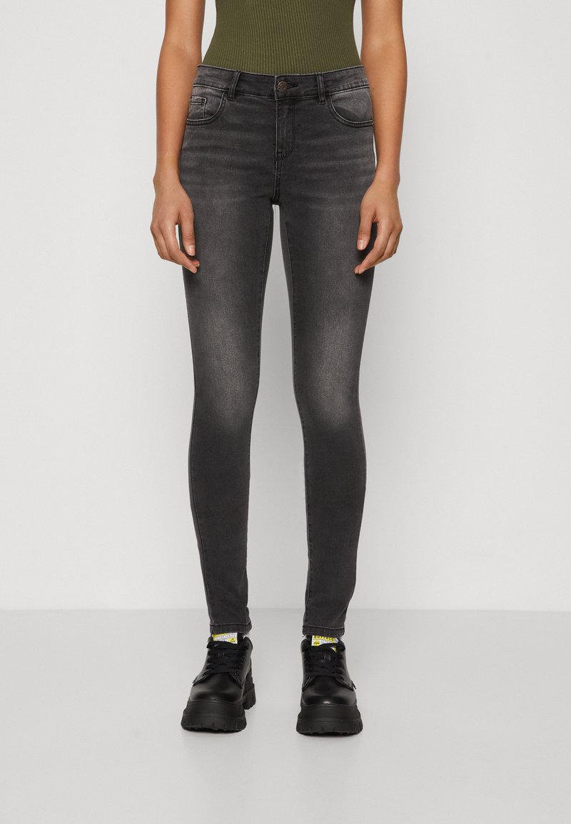 Sorte skinny jeans med en falmet vask, femlomme-design og knaplukning. Bæret med sorte chunky sneakers og en olivengrøn top.