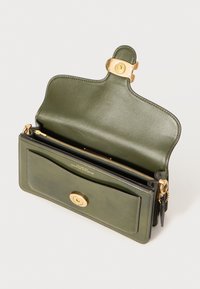 Olive green leather handbag with a smooth texture, gold hardware, and a zippered compartment. Features a magnetic closure and exterior pocket.