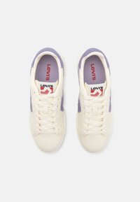 Levi's sneakers featuring a cream upper with lavender accents, textured fabric on the sides, flat laces, and branded insoles.