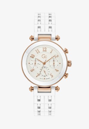 Orologio in silicone bianco con quadrante crema testurizzato, dettagli in oro rosa, grandi marcatori numerali e tre sotto-quadranti. Presenta un cinturino con motivo.