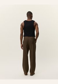 Black sleeveless tank top and brown plaid wide-leg trousers. The fabric has a smooth texture, with subtle patterns in the pants.