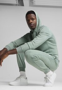 Sudadera verde clara y joggers a juego hechos de una tela suave, con puños acanalados. Zapatillas blancas completan el look casual.
