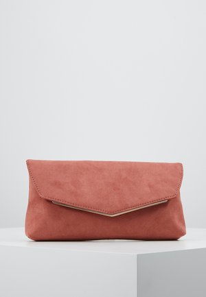 Zachte roze suède clutch met een V-vormige klep en subtiele gouden afwerking, geplaatst op een wit voetstuk tegen een lichtgrijze achtergrond.