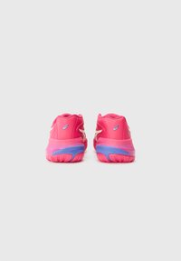 Baskets de sport roses avec un dessus en synthétique lisse, dotées d'une semelle bleue contrastante et de subtils accents blancs au niveau du talon et des côtés.