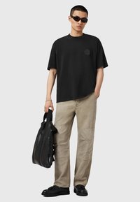 Sort bomulds T-shirt med rund hals og lille logo, parret med beige cargo bukser med syninger og sorte sneakers.