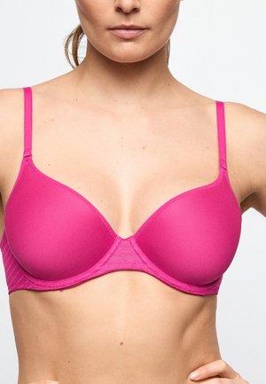 Woman wearing a bright pink underwired bra with thin adjustable straps, shown from shoulders to midriff against a plain background.