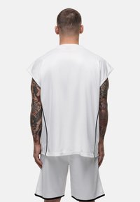 Witte sportieve shirt met korte mouwen en zijpanelen, gecombineerd met bijpassende shorts. Gekenmerkt door een lichtgewicht, ademend mesh materiaal.