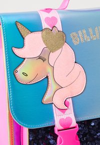 Lys blå og rosa veske med et unicorn-design, skinnende detaljer, et gullhjerte og en rosa stropp med hjerte-mønster.