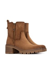 Stivali alla caviglia in suede marrone con zip laterale, tacco a blocco e suola texture. Presentano dettagli cuciti e una maniglia per indossarli facilmente.