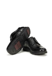 Chaussures en cuir noir avec une surface texturée, un design à lacets et des semelles en caoutchouc. Les semelles présentent des accents rouges pour une meilleure adhérence.