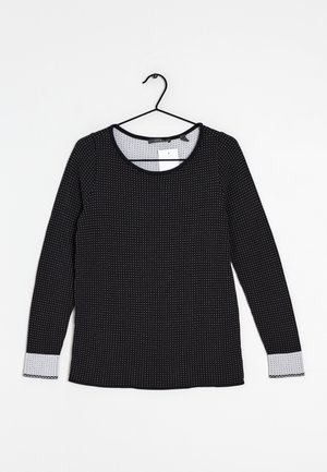 Maglietta nera a maniche lunghe con pois bianchi, scollatura tonda e rifinitura a pois grigi sui polsini. Realizzata in tessuto liscio, presenta un gancio per appenderla.