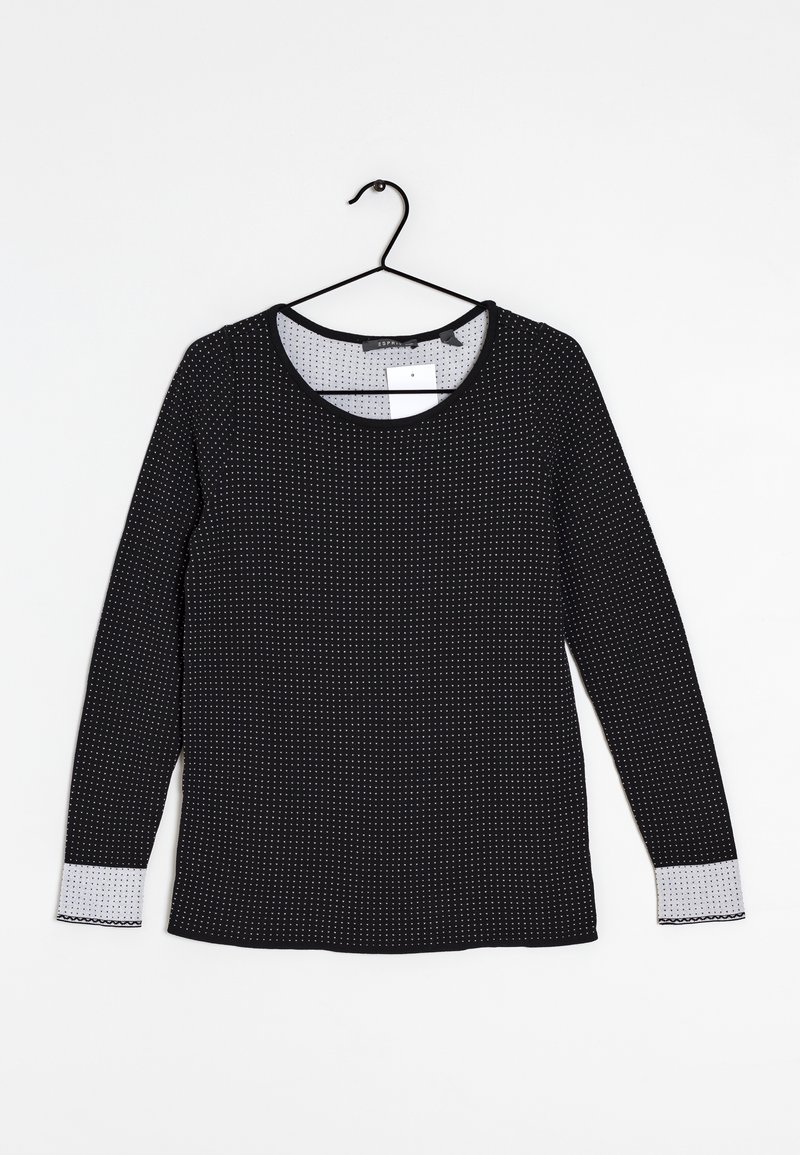 Haut noir à manches longues avec des pois blancs, col rond, et finition à pois gris au niveau des poignets. Fabriqué en tissu lisse, il présente une accroche.