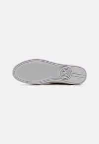 Semelle d'une basket blanche avec un motif de grip texturé et un logo circulaire comportant les lettres « MK » près du talon.