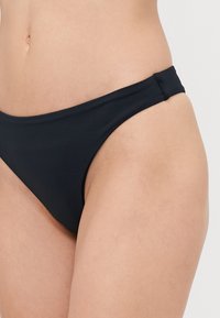 Svart bikiniunderdel med låg midja, tillverkad av mjukt, stretchigt tyg. Har minimala sid sömmar och sitter bekvämt på höfterna.