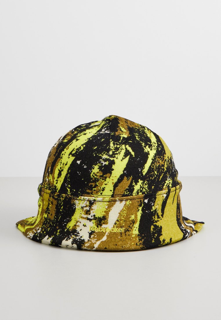 Kapelusz typu bucket z abstrakcyjnym wzorem w kolorach czarnym, żółtym, białym i brązowym, umieszczony na jednolitej jasnoszarej powierzchni.