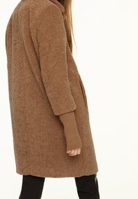 Brauner Fleece-Mantel mit einer weichen, strukturierten Oberfläche, langen Ärmeln mit gerippten Bündchen und einem geraden Schnitt, der bis zur Mitte des Oberschenkels reicht.