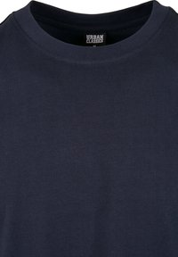 Tricou din bumbac de culoare albastru marin, cu guler rotund și mâneci scurte. Prezintă o textură moale și o etichetă cu inscripția "URBAN CLASSICS" pe interiorul gulerului.