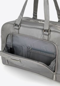 Sac fourre-tout en nylon gris avec poignées doubles, fermeture éclair en haut et plusieurs poches intérieures. Comprend des compartiments en tissu maillé et en tissu solide.