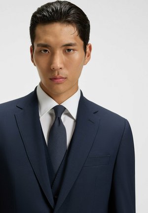 Marineblauw pak met een gestructureerde stropdas en een wit overhemd, met een notched lapel en borstzak, soepel materiaal en een op maat gemaakte pasvorm.