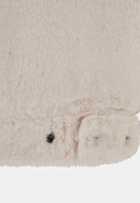 Tessuto peluche beige morbido con una consistenza soffice, caratterizzato da un piccolo dettaglio di bottone nero e bordi arrotondati.