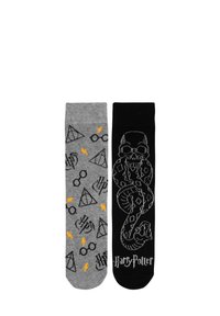 Calzini a tema Harry Potter: sinistro grigio con simboli e fulmini; destro nero con design di teschio e serpente, maglia testurizzata.