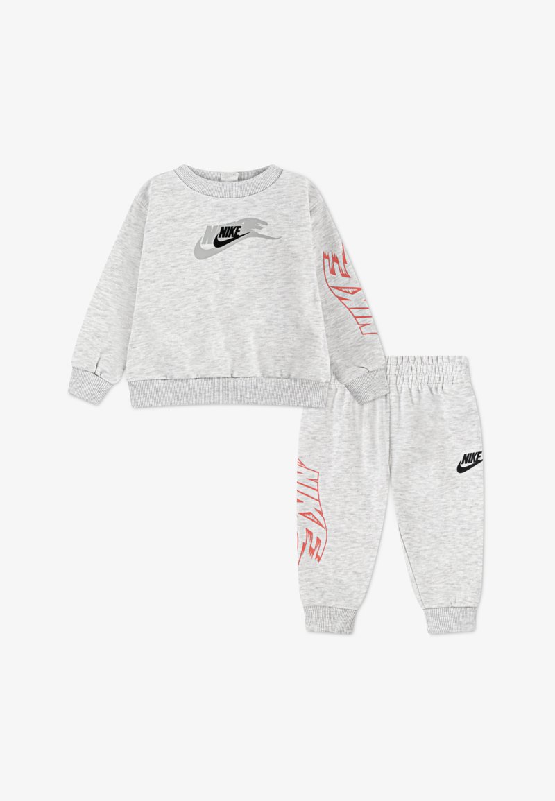 Trening gri format compus din hanorac și pantaloni, realizat dintr-un material moale. Hanoracul are un logo Nike negru și gri; pantalonii au un logo Nike negru și accente roșii.