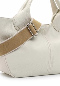 Witte, gestructureerde lederen tas met een ronde vorm, voorzien van een tan kleurige stoffen schouderband die is bevestigd met een zilveren metalen gesp. Netjes afgewerkte stiksels.