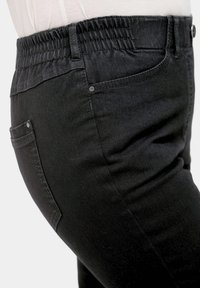 Pantalons noirs à taille élastique, avec une texture lisse, une coupe près du corps et deux poches avec des accessoires argentés contrastants.