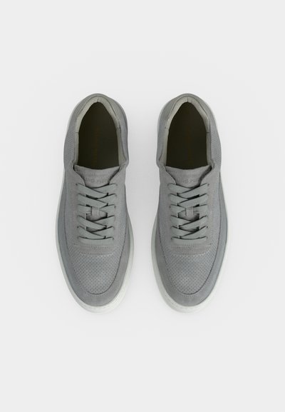 Ζευγάρι γκρι σουέντ sneakers με κορδόνια, διάτρητη περιοχή στα δάχτυλα και λευκές λαστιχένιες σόλες, σε λευκό φόντο και από ψηλά.