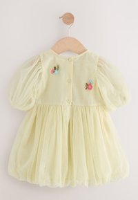 Gelbes Kleid mit Puffärmeln, aus weichem Tüllstoff, verziert mit Blumenstickerei und drei Knöpfen zum Schließen auf der Rückseite.