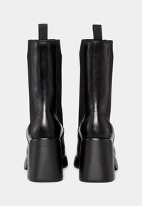 Czarne skórzane botki za kostkę z elastycznymi panelami po bokach, kwadratowymi obcasami i pętelkami do ściągania; gładka faktura z detalami przeszyć po bokach.