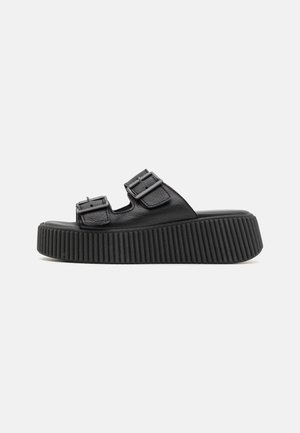 Black platform sandals with two adjustable buckle straps, textured leather upper, rounded toe, and ribbed rubber outsole.