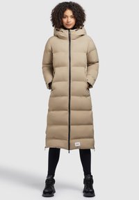 Beige langer Daunenmantel mit Kapuze, ausgestattet mit einem Frontreißverschluss, zwei Seitentaschen und einem schwarzen Besatz. Das Material wirkt glatt mit einem gesteppten Muster.