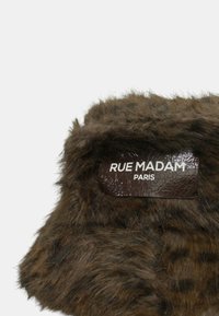 Accessorio in pelliccia sintetica marrone con etichetta lucida marrone scuro recante la scritta "RUE MADAM PARIS" in caratteri bianchi.