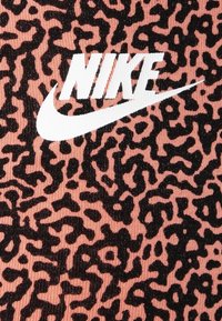 Rosa tyg med ett svart leopardsmönster, med en framträdande vit Nike swoosh-logotyp centrerad i designen.