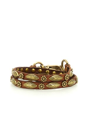 Bracciale in pelle marrone con borchie dorate a forma di fiore e foglia e una chiusura dorata, arrotolato su sfondo bianco.