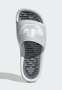 Vit glidsandal med räfflad ovandel, texturerad sula och perforerad design för andningsförmåga. Har en logotyp präglad på remmen.