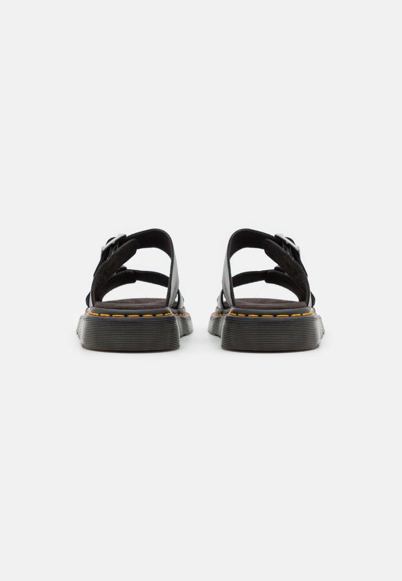Black sandals with a thick textured sole and yellow stitching, featuring open straps and adjustable buckles on the sides.