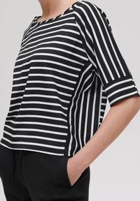 Black and white striped short-sleeve top with a boat neckline and relaxed fit, made of soft fabric, emphasizing horizontal lines.