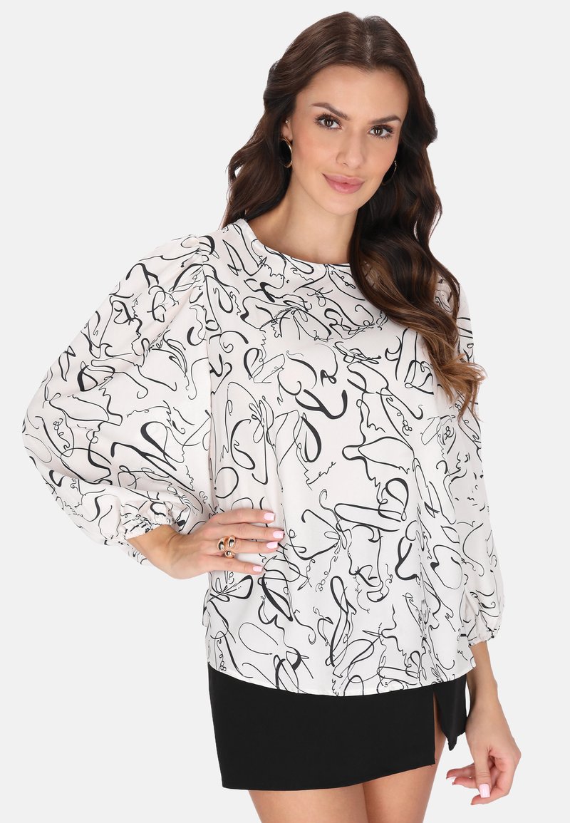 Blusa bianca con motivi astratti neri, maniche lunghe a palloncino e scollatura tonda, abbinata a una minigonna nera. Tessuto liscia.