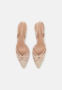 Tacchi slingback beige con punta affilata, materiale in suede morbido e dettaglio a fiocco decorativo sulla parte anteriore. Fodera interna liscia e cinturini.
