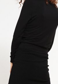 Pitkähiha Musta Paita, joka on valmistettu pehmeästä kankaasta, yhdistettynä ribattyyn mustaan hameeseen. Molemmat on suunniteltu sopivaksi tyyliksi, yksinkertaisella ja saumatonta ulkoasua.