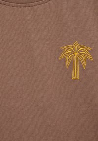 Tissu marron avec un simple motif de palmier jaune brodé près de l'encolure.
