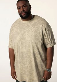 Beige kortærmet t-shirt med et struktureret mønster. Løs pasform med en rund halsudskæring. Stoffet føles blødt og let.
