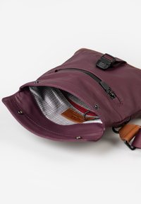 Lila Tasche mit glatter Textur, ausgestattet mit einer Reißverschlusstasche, kariertem Futter, Lederakzenten und verstellbarem Tragegurt.