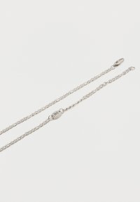 Δύο λεπτές αλυσίδες από ασήμι με οβάλ κρίκους, η μία με κούμπωμα-σφεντόνα και η άλλη με κούμπωμα σε σχήμα οβάλ ταμπελίτσας με επωνυμία.