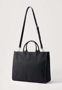 Svart tote-veske med en teksturert stoffkropp, glatte lærdetaljer, to korte håndtak og en avtakbar, justerbar skulderrem.